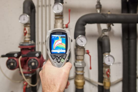 Plumber using a thermal imaging camera to inspect pipes in Pueblo