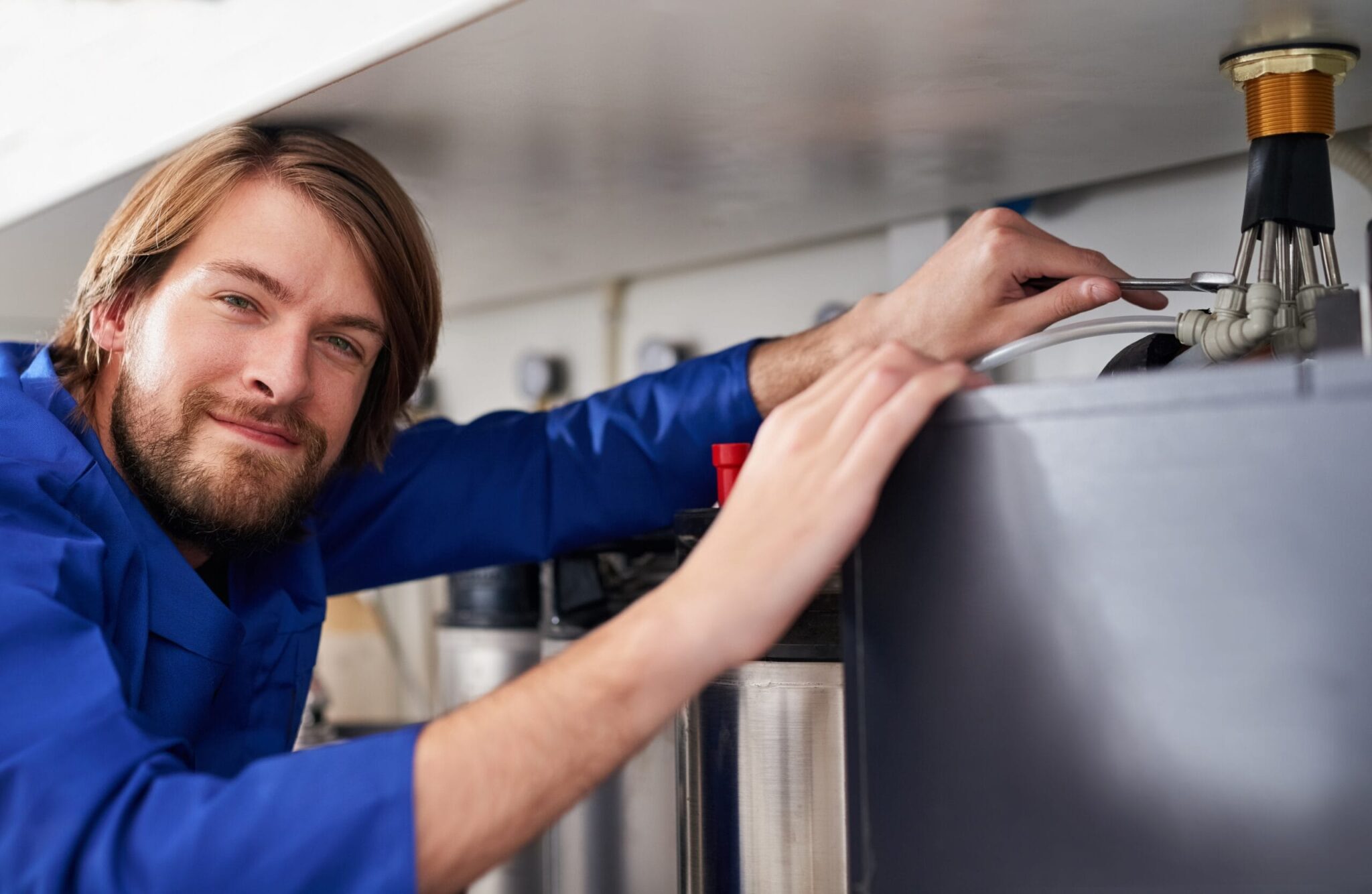 Technician servicing a residential water heater tank in Pueblo